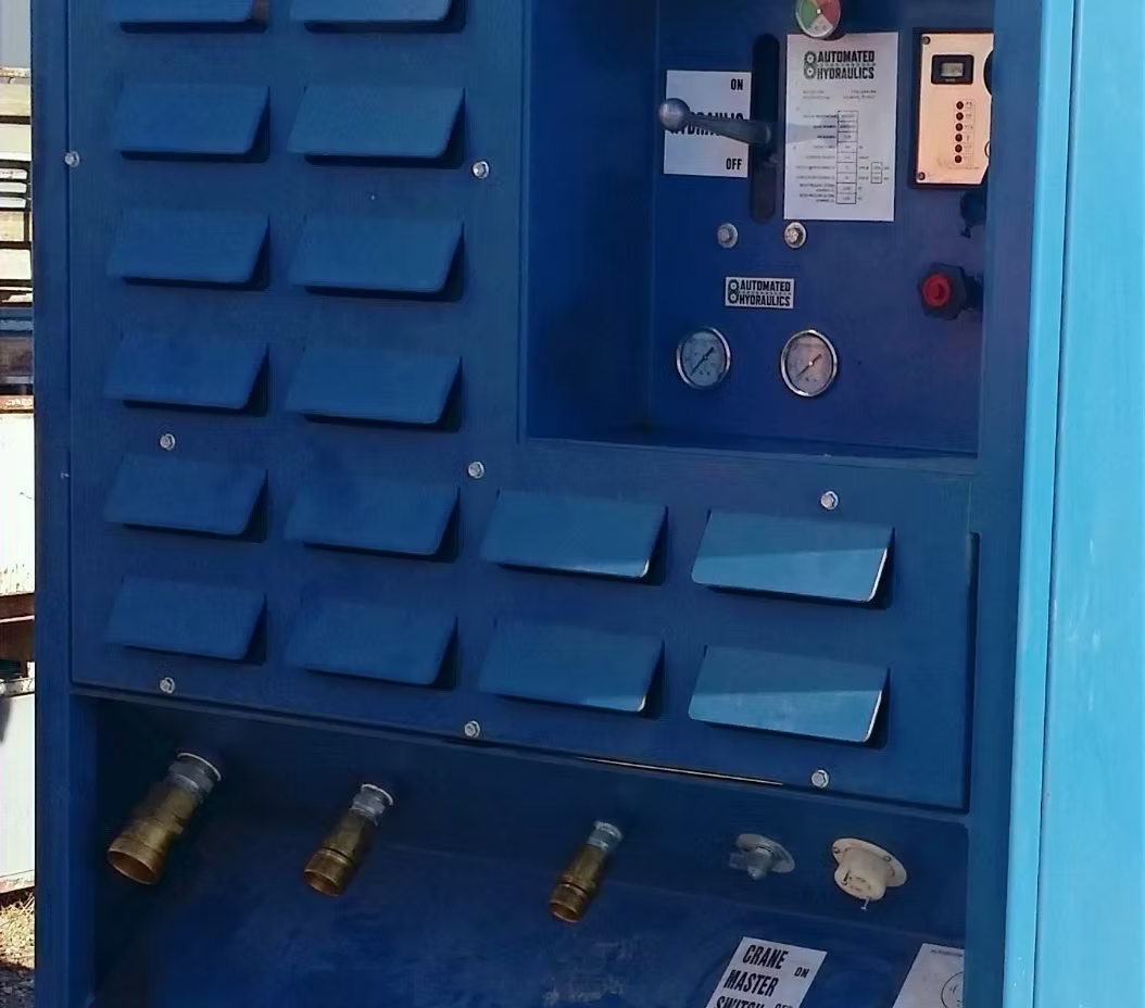 Blue industrial control panel with gauges, switches, and hydraulic components